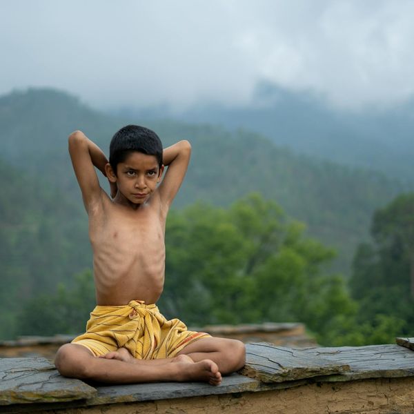 A serene person practicing a balance pose outdoors with nature in the background.